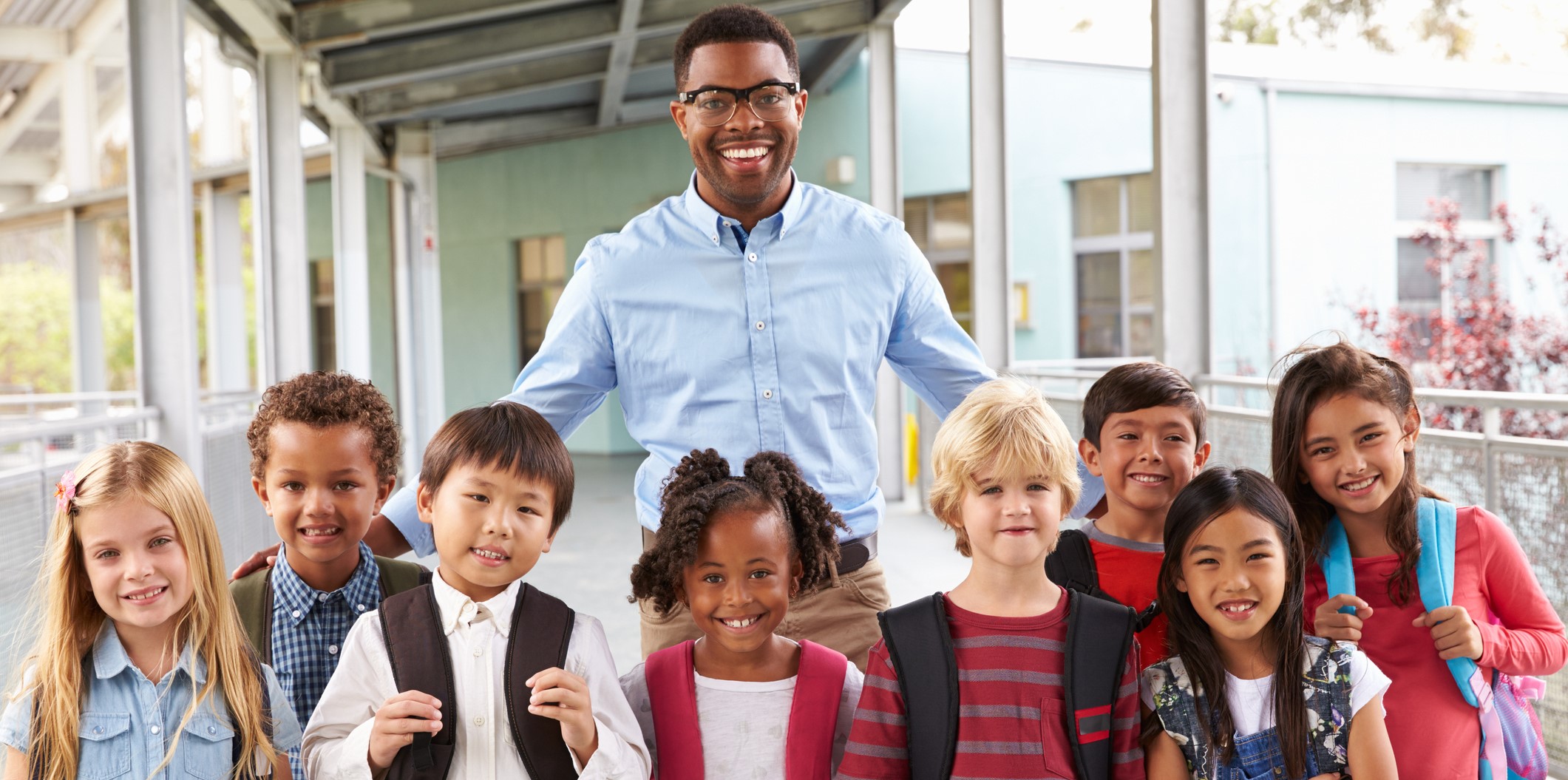 An adult male with students in a school hallway